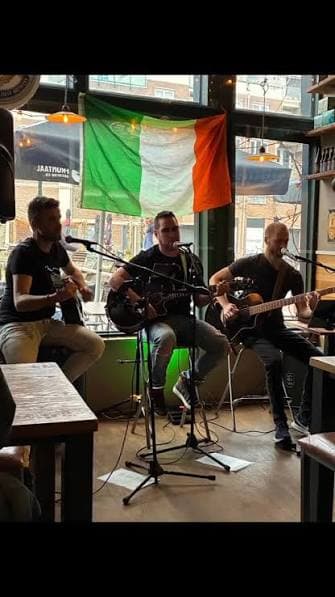 The Lonesome Lads spelen live in het café, met de Ierse vlag op de achtergrond